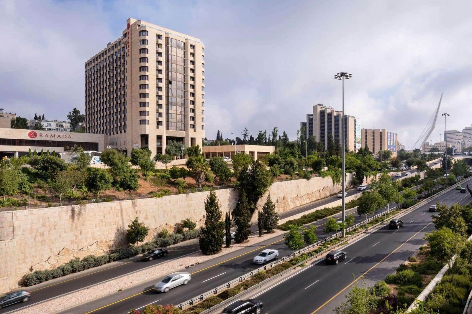 A multi-story hotel with a modern design, located adjacent to a busy highway.