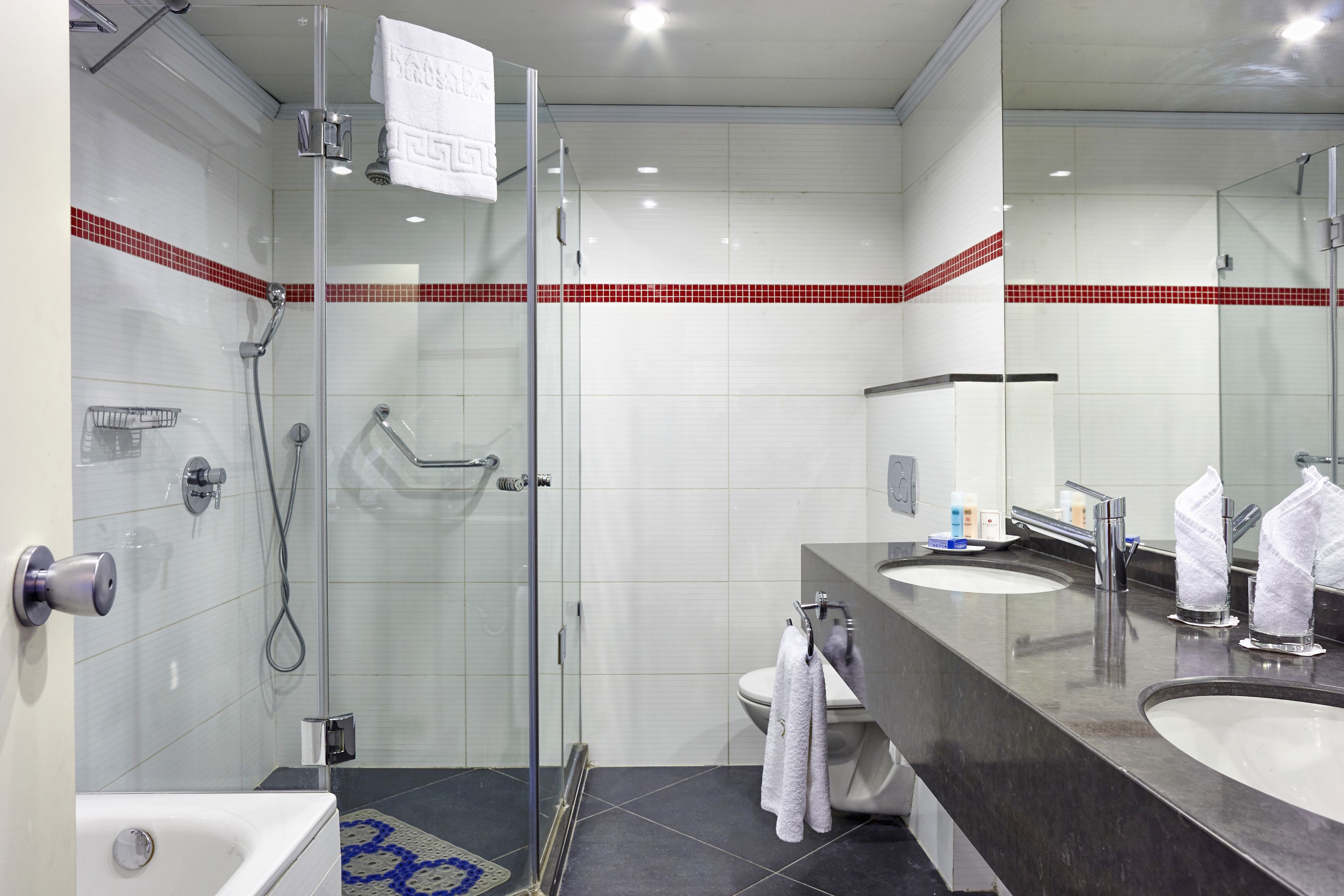 Ein modernes Badezimmer mit Duschkabine aus Glas, einer Badewanne, zwei Waschbecken und einem großen Spiegel.