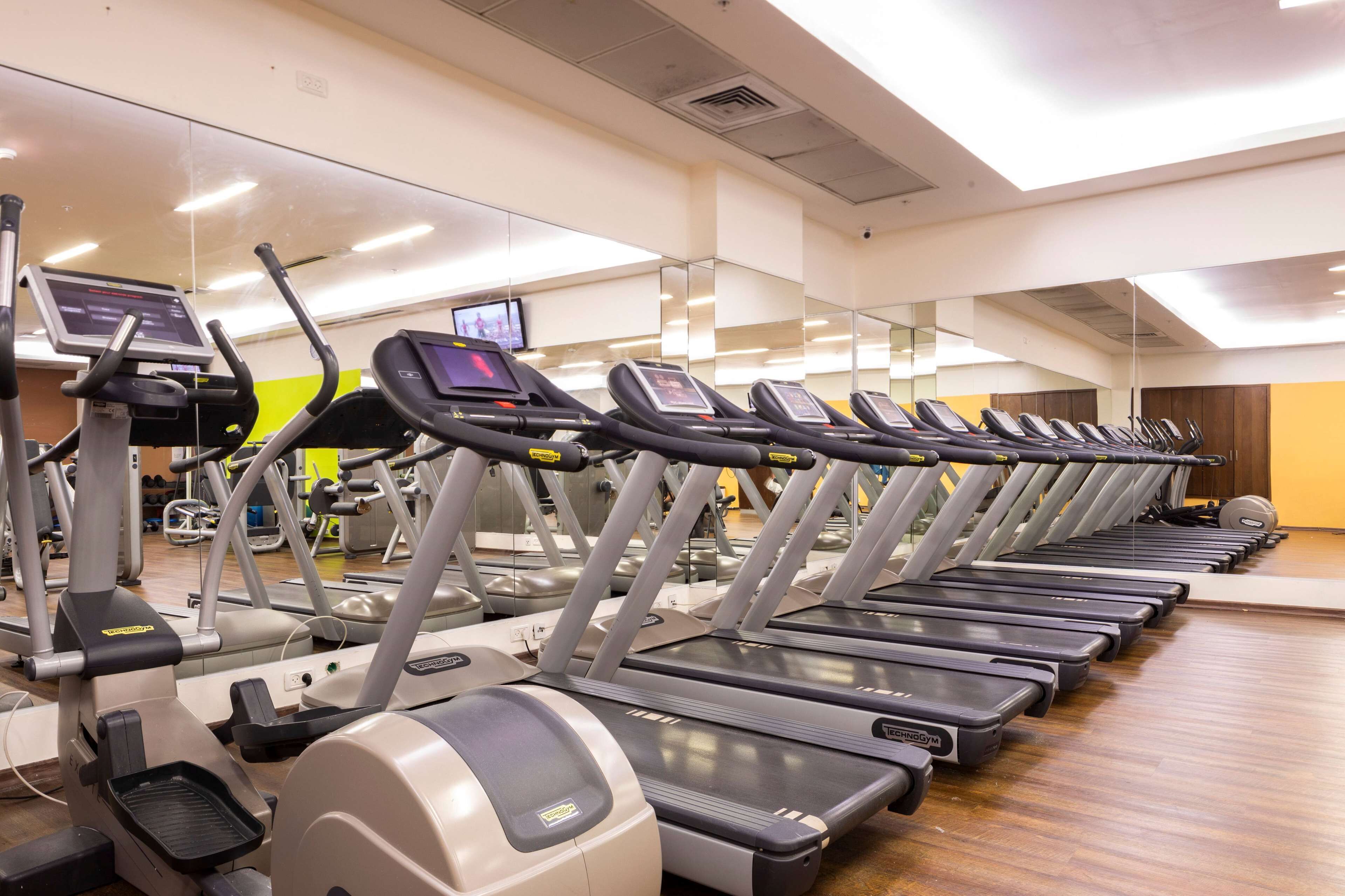 A row of treadmills in a gym with mirrors on the walls.
