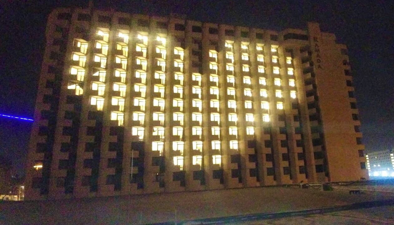Un rascacielos con numerosas ventanas iluminadas durante la noche.