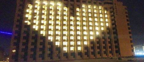 Un rascacielos con numerosas ventanas iluminadas durante la noche.