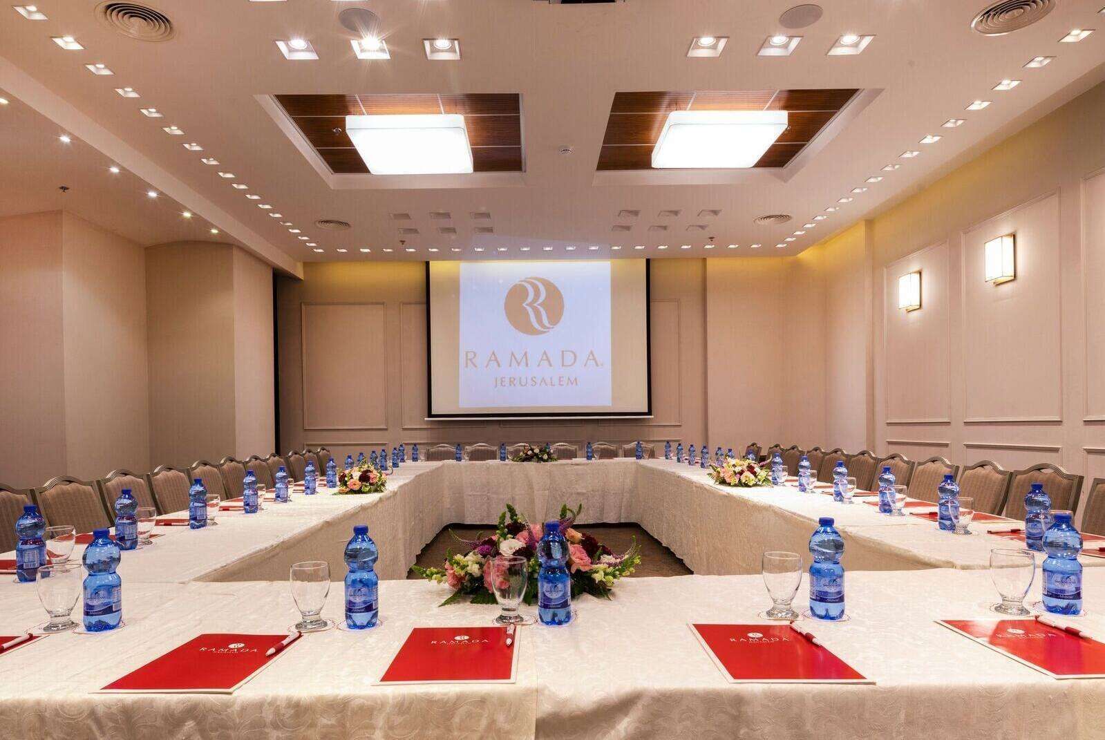 Un salón de conferencias con una larga mesa, botellas de agua y tarjetas de identificación rojas.
