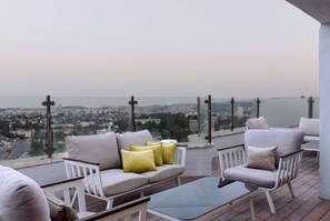 A balcony with a sofa and armchairs, overlooking a cityscape. - Ramada by Wyndham Jerusalem (Jerusalem)