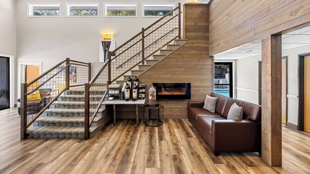 A spacious living area with a wooden staircase, a fireplace, a sofa, and a coffee table. - Best Western Inn At The Rogue (Grants Pass)