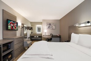 A hotel room with a bed, a desk, a chair, a television, a microwave, a sink, and a mirror. - Red Roof Inn PLUS+ Chicago - Naperville (Naperville)