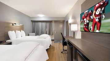 Una habitación de hotel con dos camas, un televisor en la pared, un escritorio y una silla.