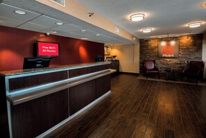 A hotel reception area with a digital display advertising free Wi-Fi, a coffee machine, and a sign for Red Roof Plus. - Red Roof Inn PLUS+ Chicago - Naperville (Naperville)