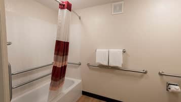 Un baño con bañera, cortina de ducha, toallero y porta papel higiénico.