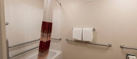 A bathroom with a bathtub, a shower curtain, a towel rack, and a toilet paper holder.
