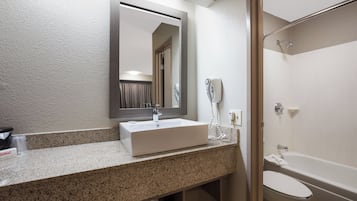 A bathroom with a sink, mirror, shower, and toilet.