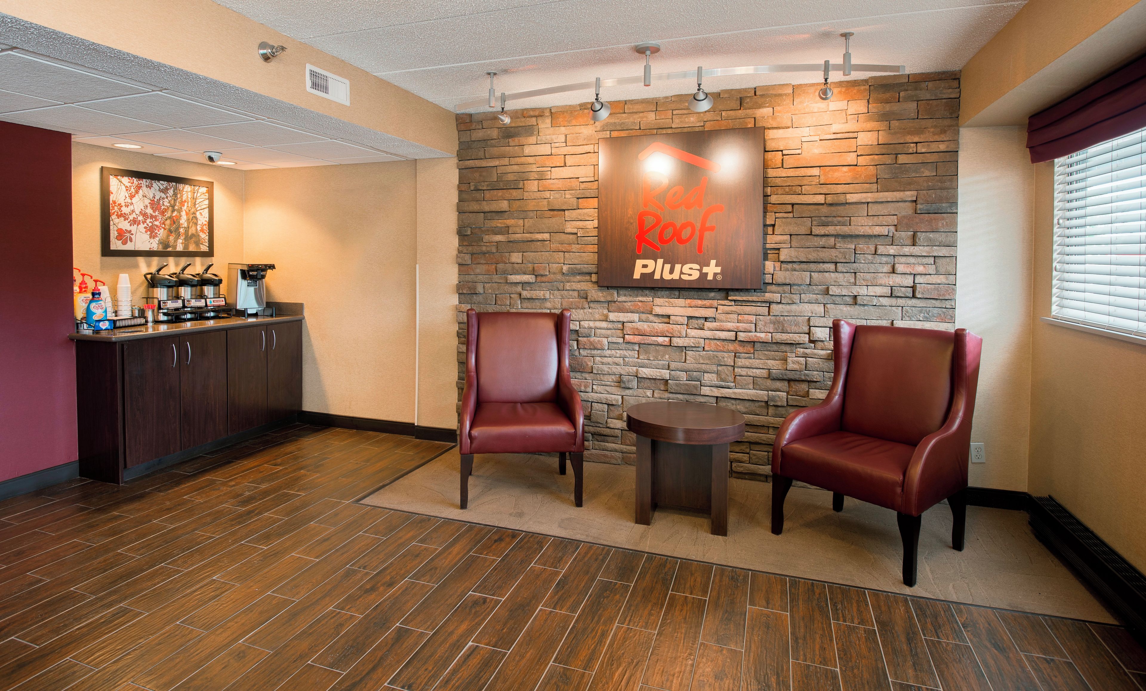 A reception area with a stone wall, two leather chairs, a coffee station, and a sign reading 'Red Rock Plus'.
