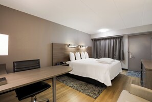 A hotel room with a bed, bedside table, desk, chair, and a wardrobe. - Red Roof Inn PLUS+ Chicago - Naperville (Naperville)