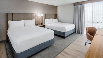 A hotel room with two beds, a desk, and a chair.