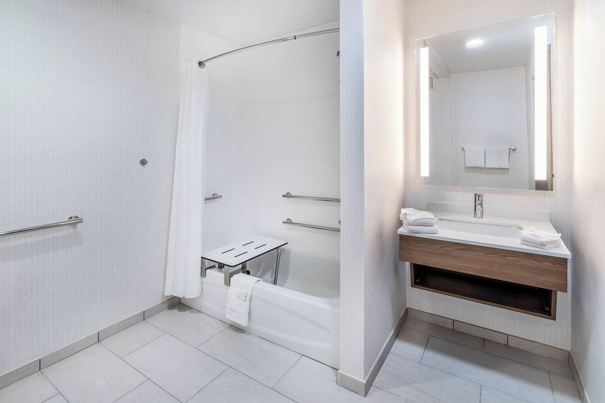 A modern bathroom with a walk-in shower, a bathtub, a vanity with a mirror, and a towel rack.