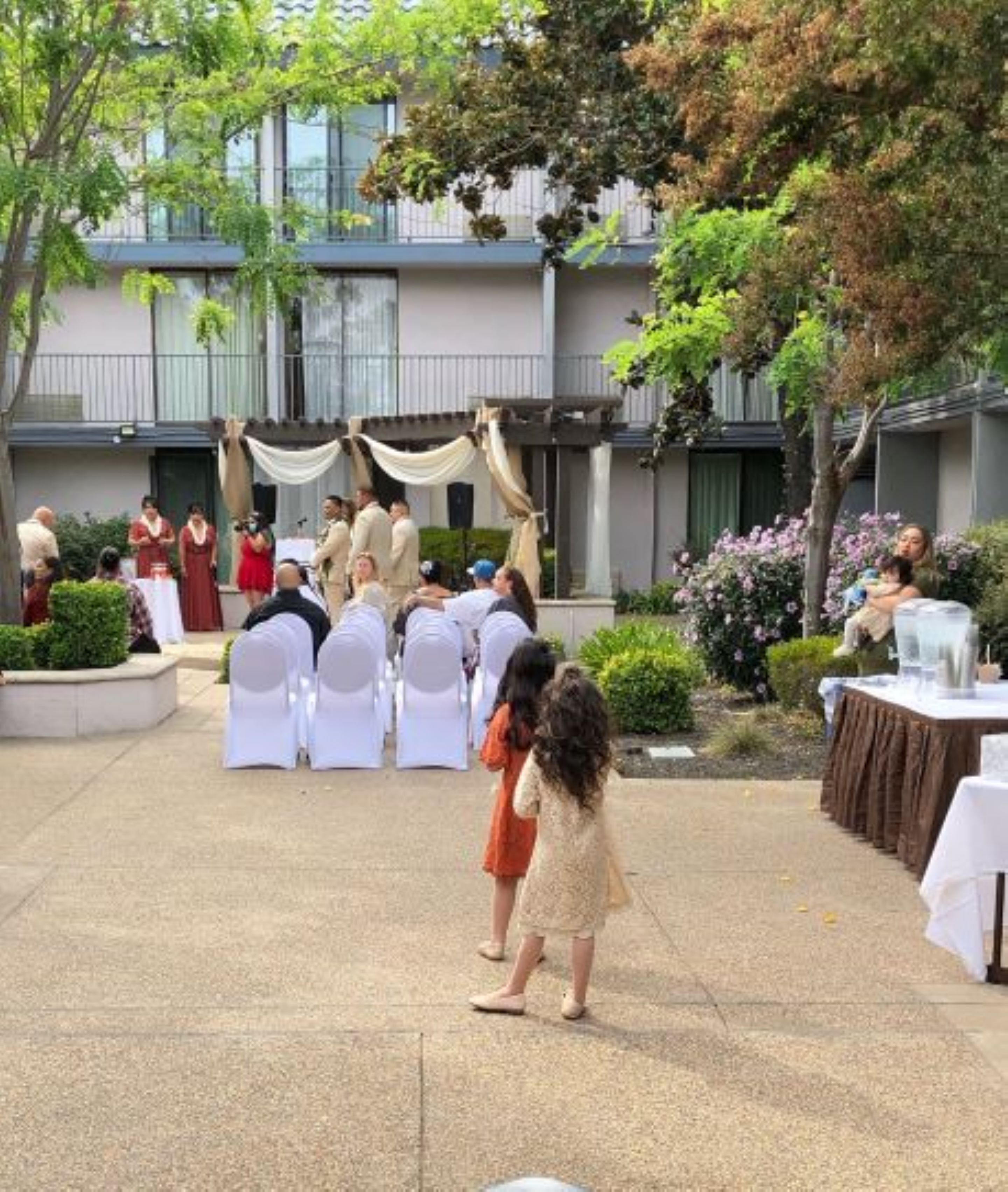 Evento al aire libre con escenario, invitados sentados y un entorno de jardín.
