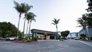 A hotel entrance with a covered parking area, palm trees, and a modern building facade. - Holiday Inn Dublin-Pleasanton by IHG (Dublin)