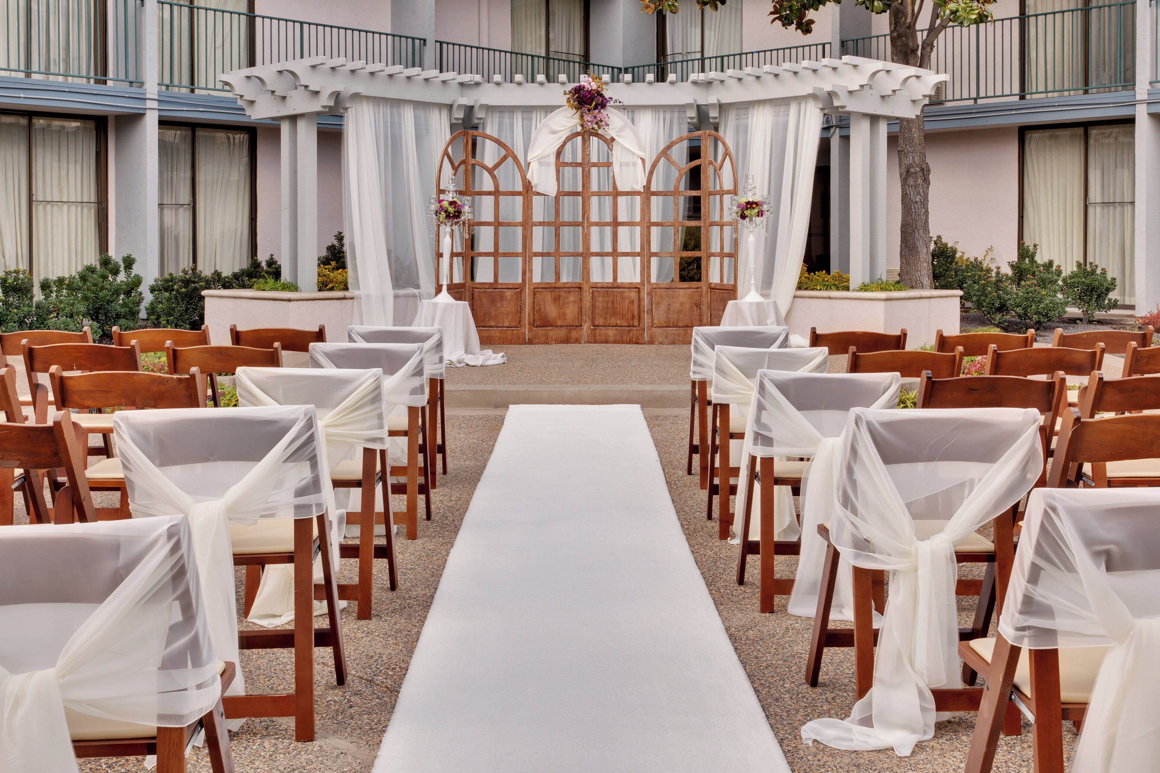 Une cérémonie de mariage en plein air, avec des rangées de chaises en bois et une allée blanche.