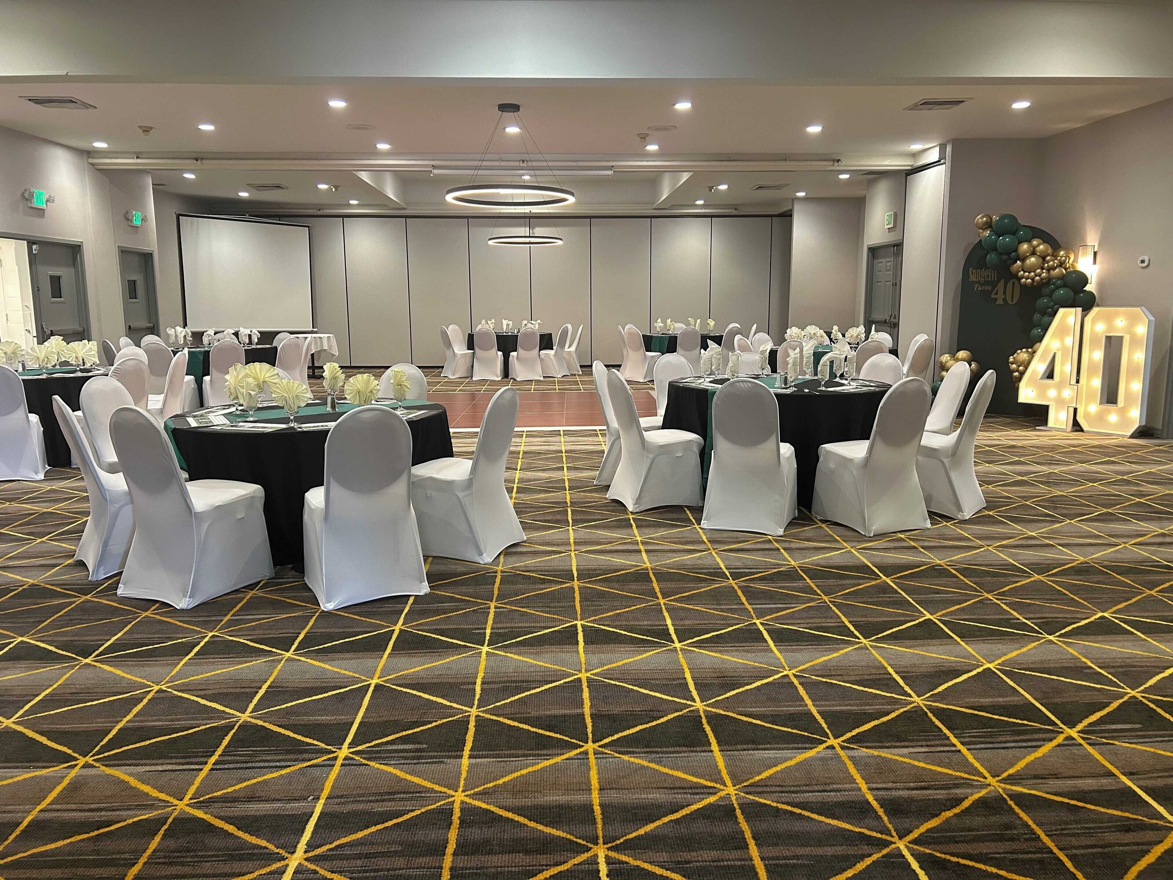 A conference room with tables and chairs, a patterned carpet, and a large illuminated number 40 sign.
