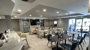 A modern restaurant with a marble counter, multiple tables and chairs, and large windows providing natural light. - Holiday Inn Dublin-Pleasanton by IHG (Dublin)