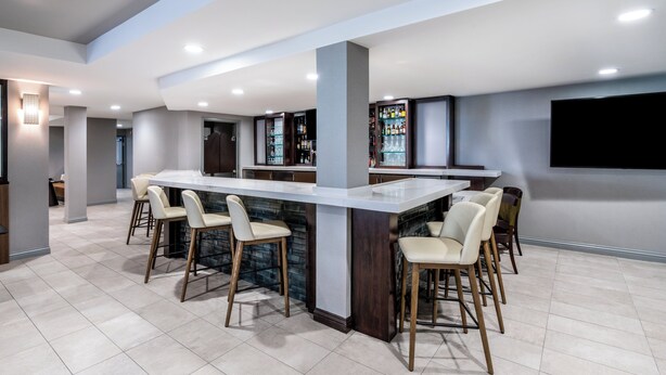 A modern kitchen with a central island, bar stools, and a built-in bar area with shelves of bottles. - Holiday Inn Dublin-Pleasanton by IHG (Dublin)