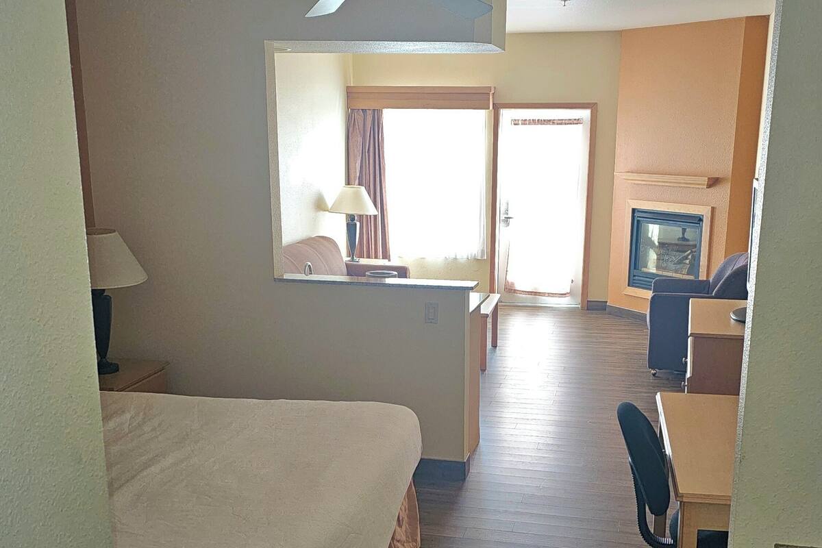 A hotel room with a bed, a desk, a chair, a television, and a ceiling fan.