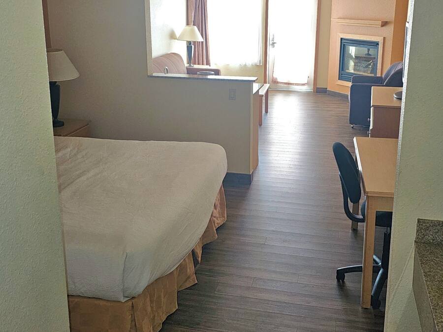 A hotel room with a bed, a desk, a chair, a television, and a ceiling fan.