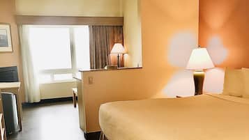 A hotel room with a large bed, two bedside lamps, a desk, and a chair.