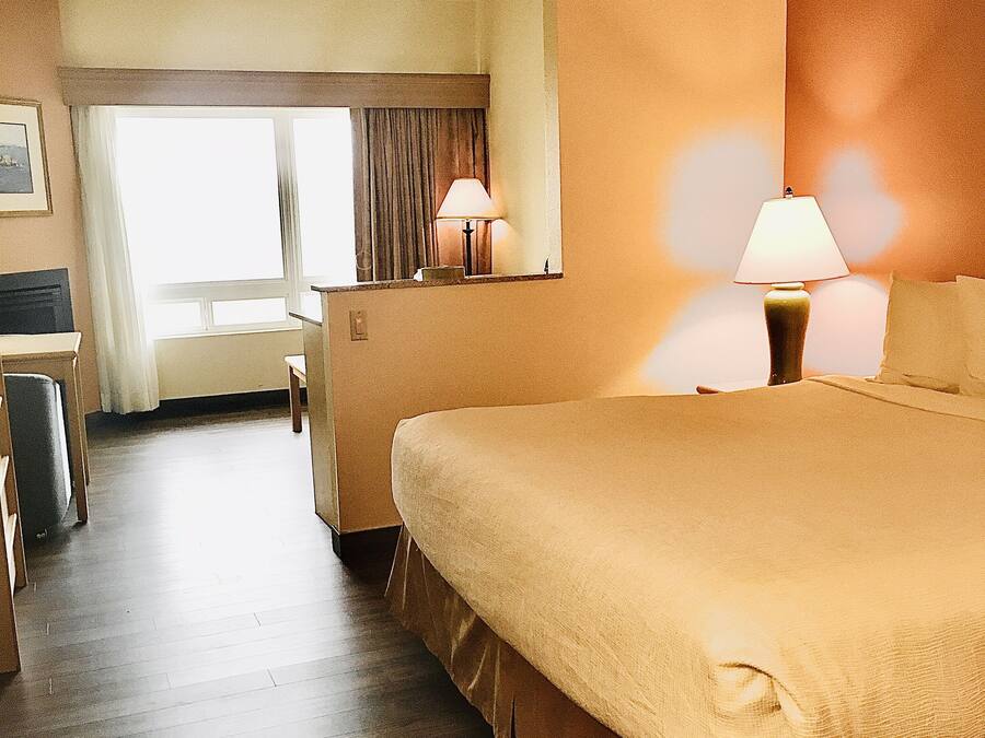 A hotel room with a large bed, two bedside lamps, a desk, and a chair.