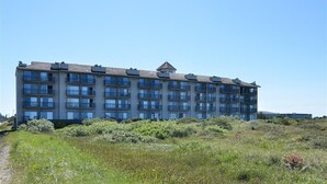 A multi-story building with a flat roof, several balconies, and a pathway leading to the entrance. - Lighthouse Suites Inn (Ocean Shores)