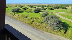 A view from a balcony overlooking a coastal landscape with green fields and a clear blue sky. - Lighthouse Suites Inn (Ocean Shores)