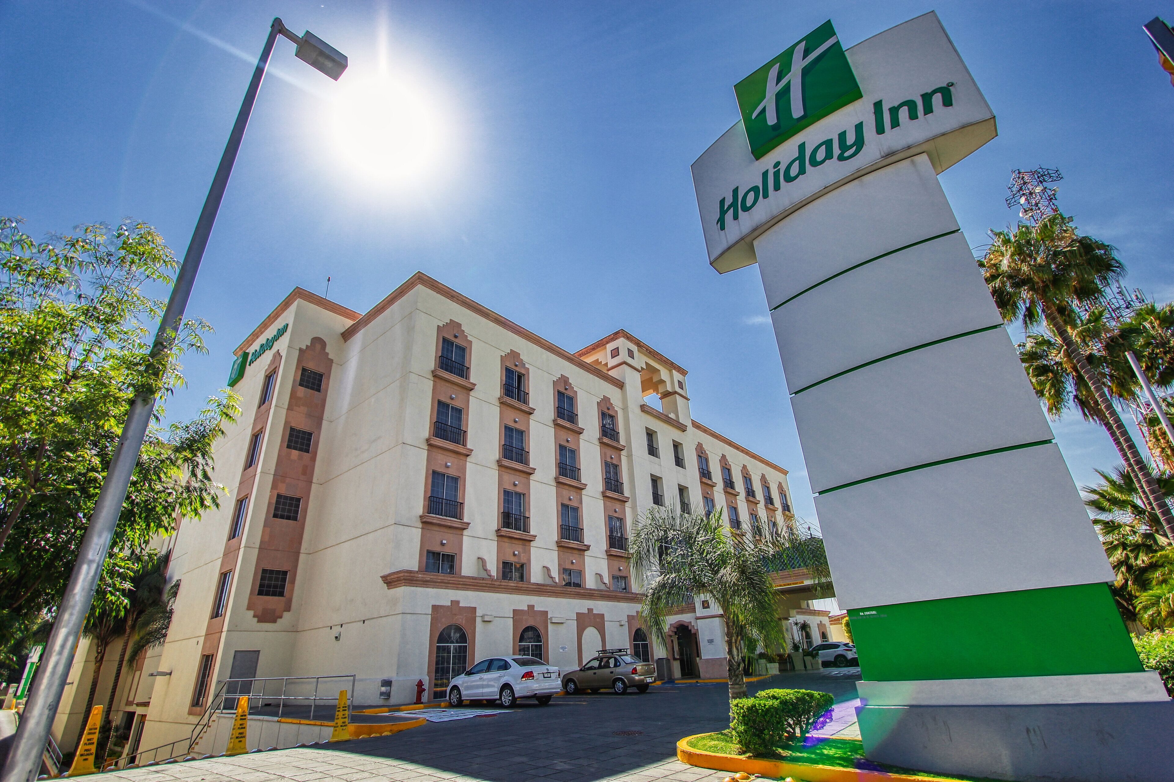 A Holiday Inn hotel with a large building, a parking lot, and a street lamp.