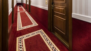 A hotel hallway with a red carpet, wooden doors, and white walls. - Phi Hotel Principe (Cuneo)