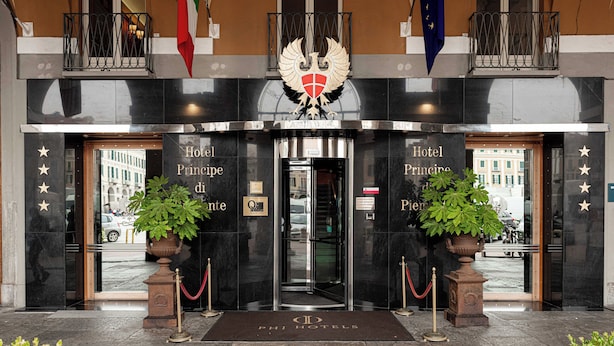 The entrance of Hotel Principe with a double door, a coat of arms, and two potted plants. - Phi Hotel Principe (Cuneo)