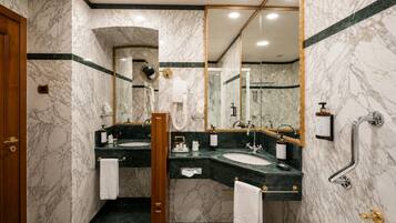 A marble bathroom with two sinks, a mirror, a toilet, and a shower.