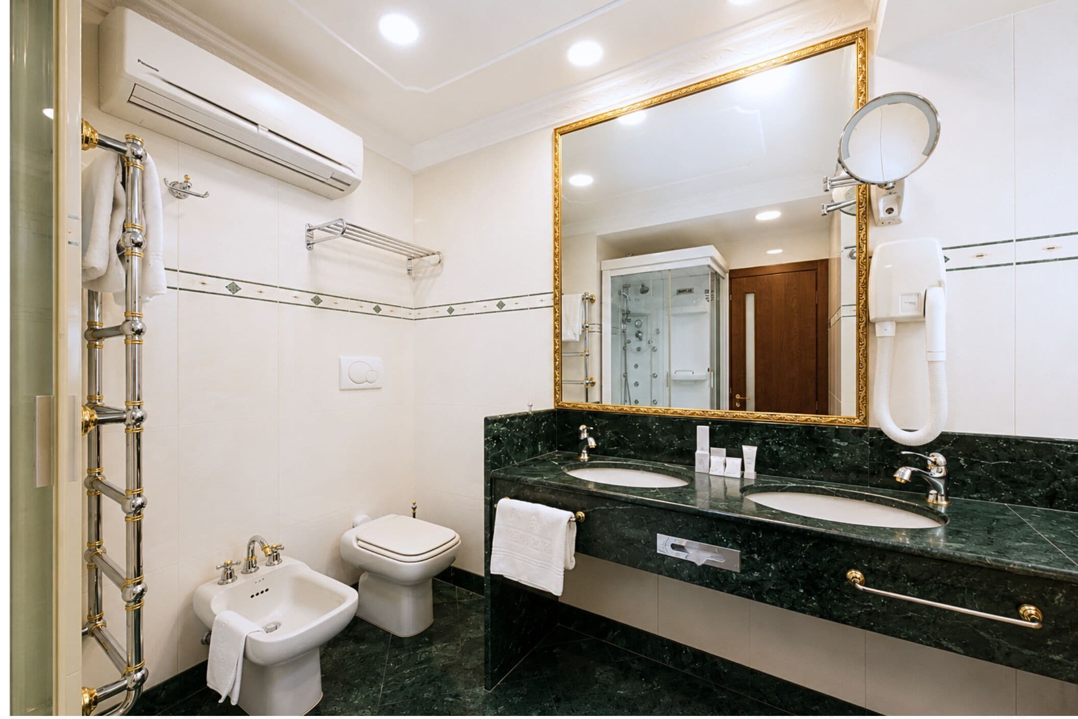 Un bagno con un grande specchio, due lavandini, un bidet e una doccia.