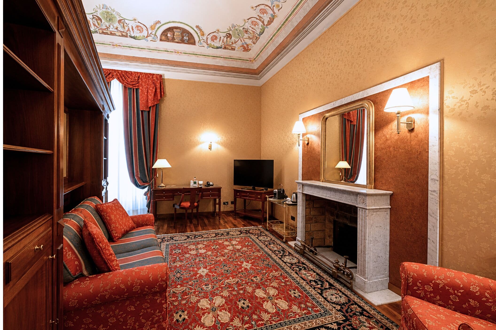 A room with a fireplace, a television, a desk, and a sofa.