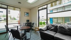 A room with a leather sofa, two chairs, a small table, and large windows with a view of the outside. - Loyalty Inn Maryville (Maryville)