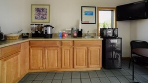 A compact kitchen with wooden cabinets, a refrigerator, and a microwave. - Loyalty Inn Maryville (Maryville)