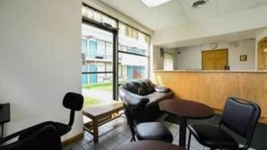 A room with a reception desk, a sofa, a small table, and a chair. - Loyalty Inn Maryville (Maryville)