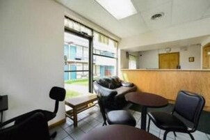 Um quarto com uma mesa de recepção, um sofá, uma pequena mesa e uma cadeira.