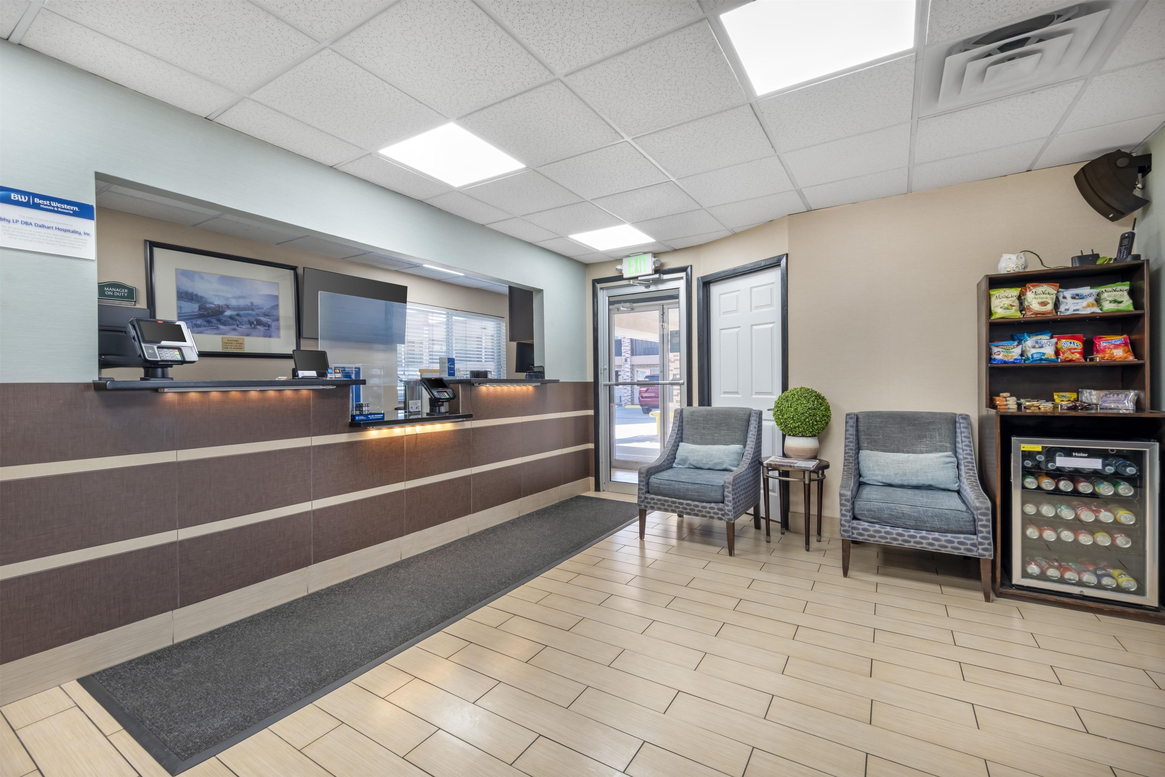 A reception area with a reception desk, chairs, a vending machine, and a door leading outside.
