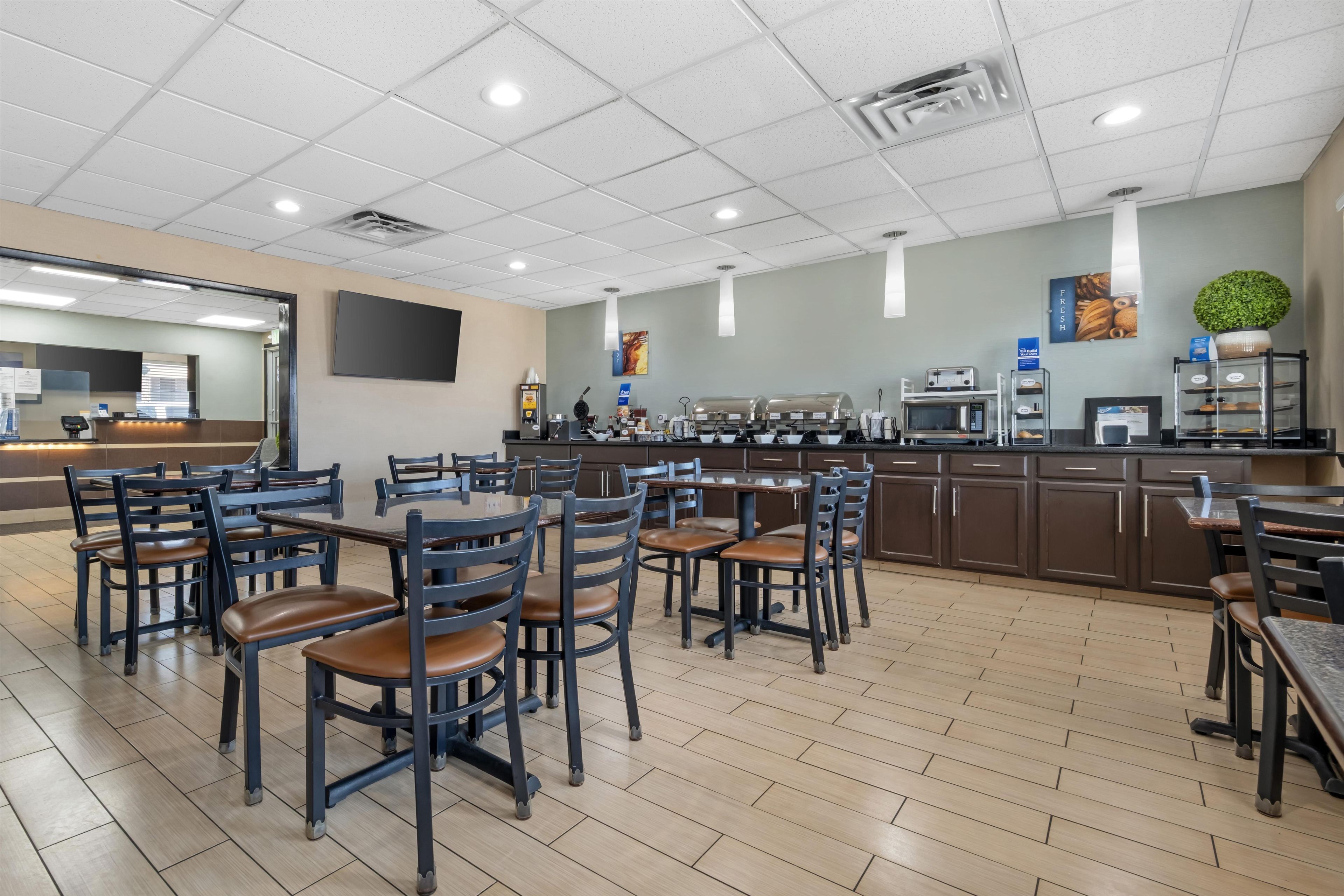 Eine Cafeteria mit mehreren Tischen und Stühlen, einer Kaffeestation und einer Mikrowelle.