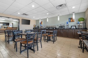 Una cafetería con varias mesas y sillas, una estación de café y un microondas.