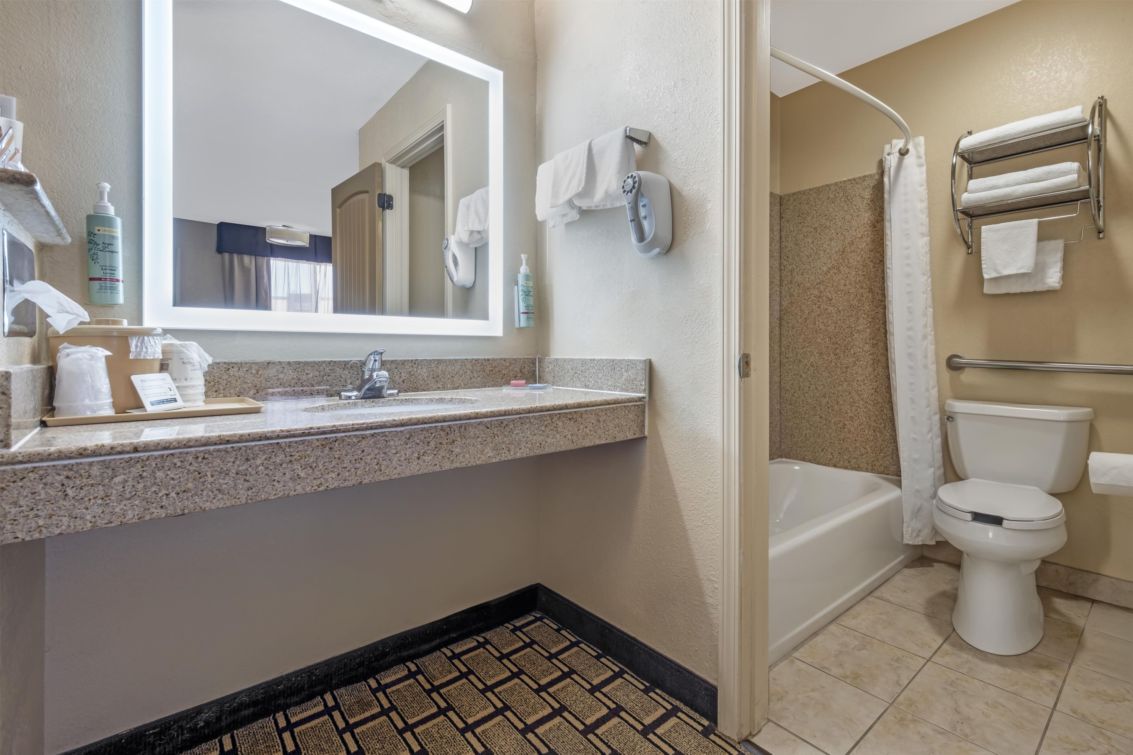 A bathroom with a sink, mirror, shower, and toilet.