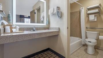A bathroom with a sink, mirror, shower, and toilet.