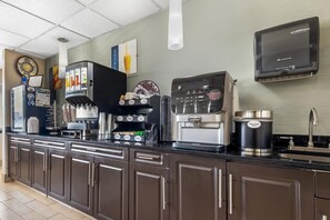 Una cocina comercial con una máquina de café, un dispensador de bebidas y una cafetera.