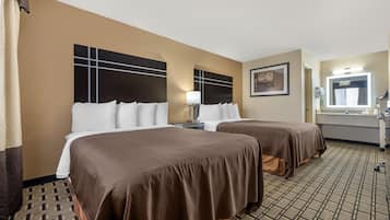 A hotel room with two beds, a large mirror, a painting, and a patterned carpet.