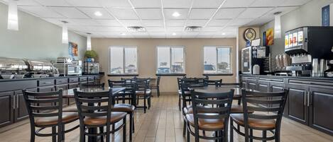 A restaurant with a modern interior, featuring a kitchen area, dining tables, and chairs.