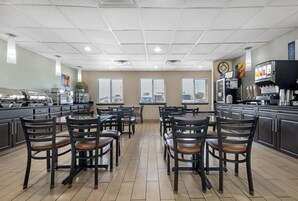 Un restaurante con un interior moderno, que cuenta con una zona de cocina, mesas y sillas.