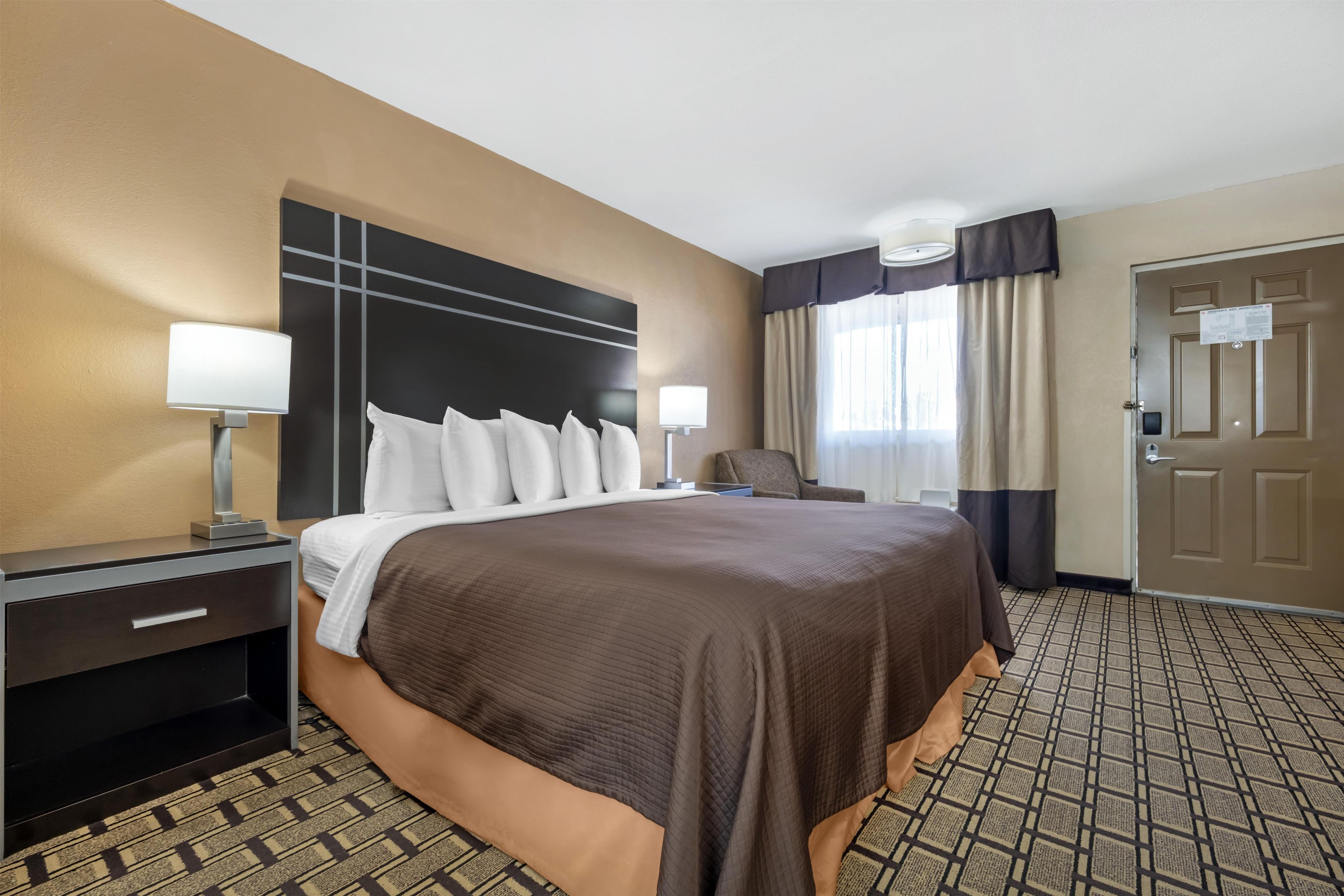Une chambre d’hôtel avec un grand lit, des tables de chevet, un bureau et une chaise.